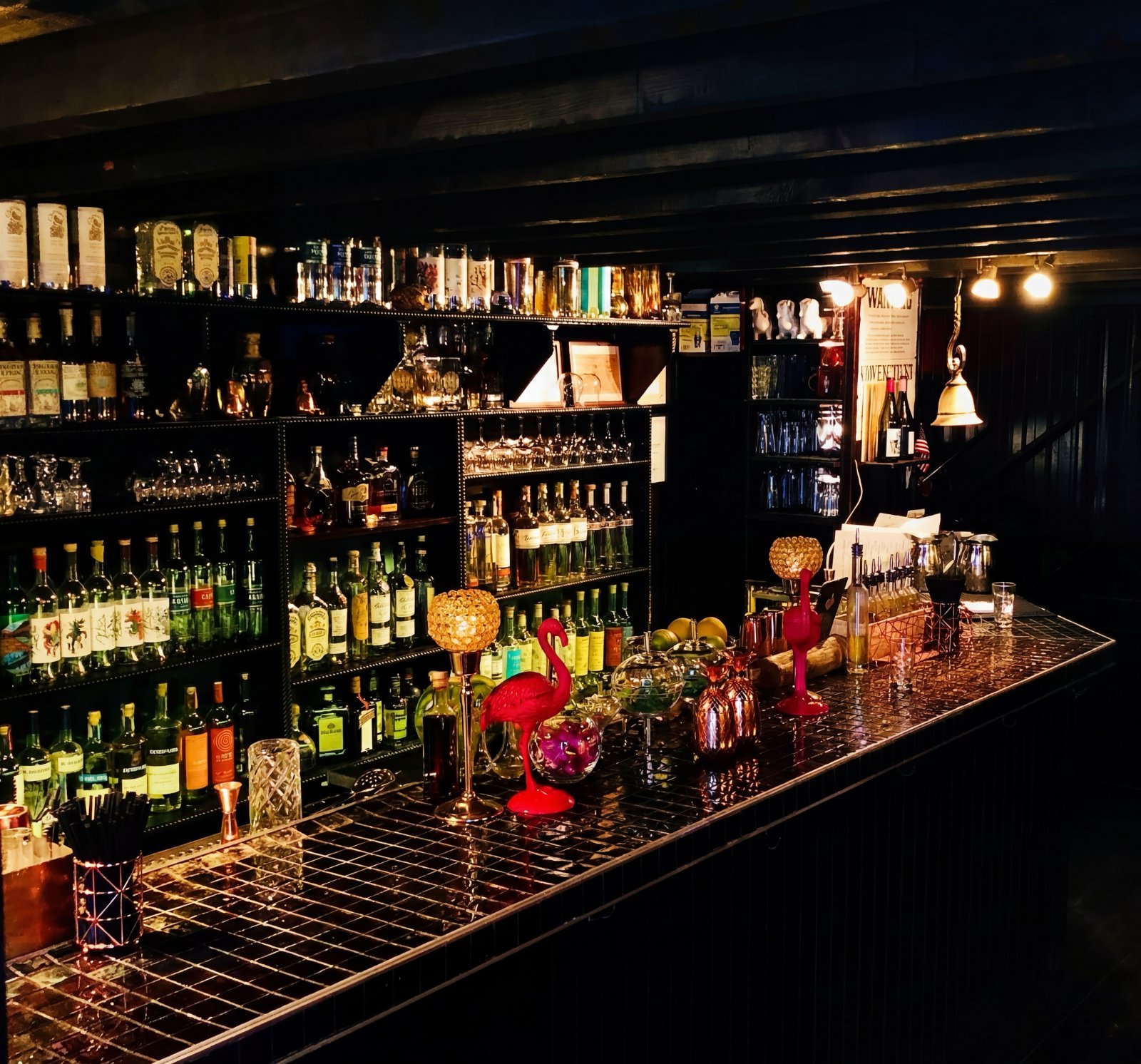 The dimly lit Maya Mezcal bar interior, lined with bottles and candles